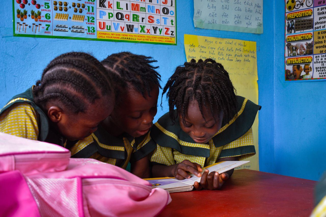 Three young African girls reading at a school in Monrovia, Liberia.